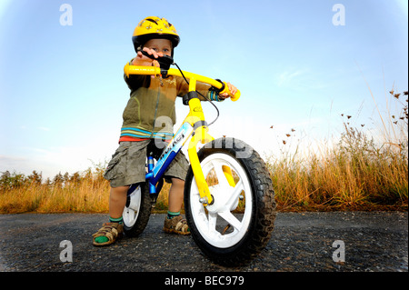 Garçon enfant randonnée à vélo à travers une forêt en vélo avec casque de vélo Banque D'Images