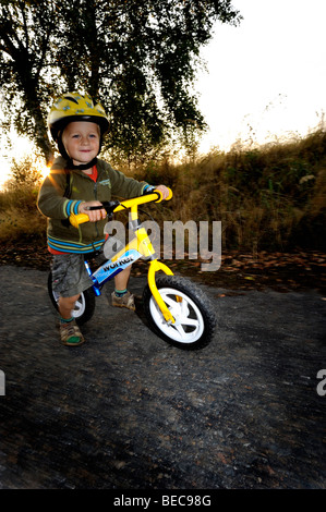 Garçon enfant randonnée à vélo à travers une forêt en vélo avec casque de vélo Banque D'Images