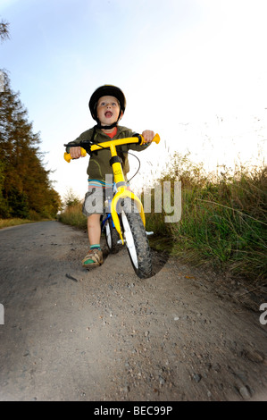 Garçon enfant randonnée à vélo à travers une forêt en vélo avec casque de vélo Banque D'Images