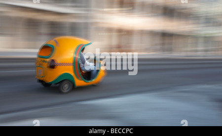 Cocotaxi, coco taxi, accélérant le long de la route, à l'El Malecon, La Havane, Cuba, Antilles, Caraïbes, Amérique Centrale Banque D'Images