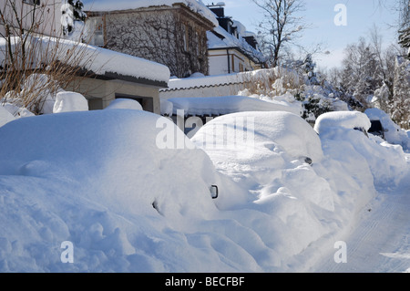 Voitures couverts dans la neige profonde sur le bord de la route Banque D'Images