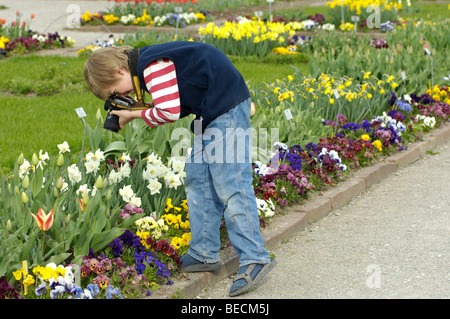 Petit garçon, 10, à photographier des fleurs Banque D'Images