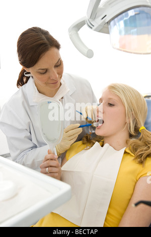 La vérification d'un dentiste dents de la jeune fille, girl avec un petit miroir Banque D'Images