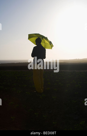 Farmer holding un parapluie dans le domaine, en Californie, USA Banque D'Images