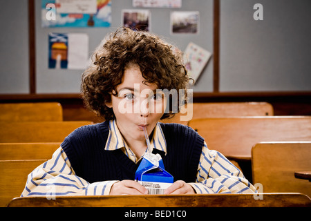 Boire du jus d'écolier dans une salle de classe Banque D'Images