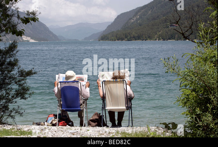 Couple retraité lire le journal sur la banque de l'Achensee Lake près de Pertisau, Tyrol, Autriche, Europe Banque D'Images