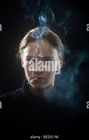 Portrait d'une jeune femme fumant une cigarette, la fumée Banque D'Images