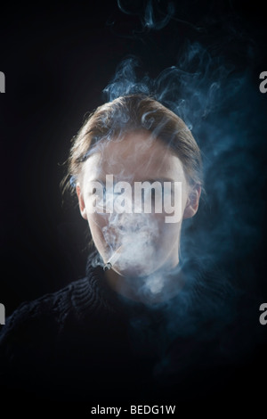 Portrait d'une jeune femme fumant une cigarette, la fumée Banque D'Images