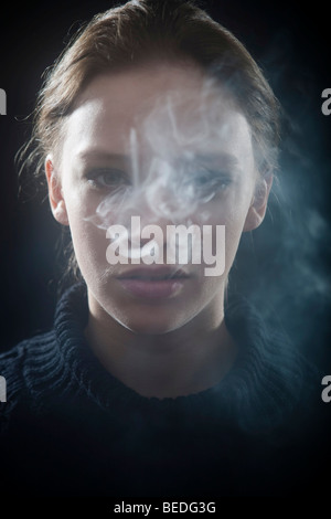 Portrait d'une jeune femme fumant une cigarette, la fumée Banque D'Images