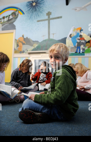 Un GROUPE DE QUATRE FILLES ET DEUX GARÇONS LA LECTURE D'UNE BIBLE ENSEMBLE À UNE ÉCOLE DU DIMANCHE UK Banque D'Images