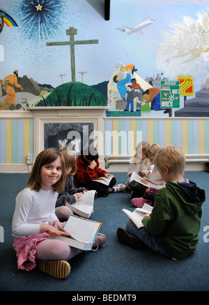 Un GROUPE DE QUATRE FILLES ET DEUX GARÇONS LA LECTURE D'UNE BIBLE ENSEMBLE À UNE ÉCOLE DU DIMANCHE UK Banque D'Images