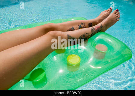 Tattoo'd jambes sur un lilo Banque D'Images