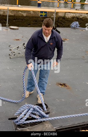 Tug boat liens travailleur figure huit noeud pour fixer à l'écluse barge pendant 15 à Fort lisse sur Canal Erie Banque D'Images