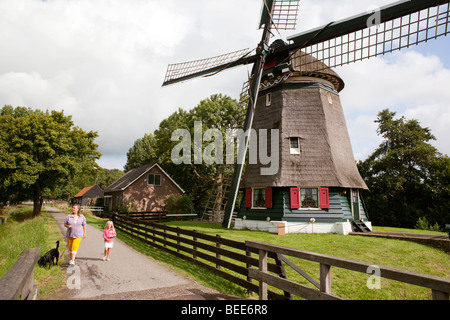 Mère et fille de promener le chien le long d'un moulin à vent. Edam, Pays-Bas Banque D'Images