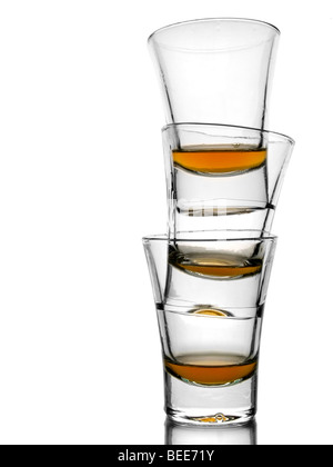 Une pile de trois onces de whisky presque vide sur fond blanc avec reflex. Banque D'Images