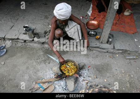 Tatopani, Népal - 01 avril 2008. Vieux sadhu préparer un repas végétarien sur feu ouvert Banque D'Images