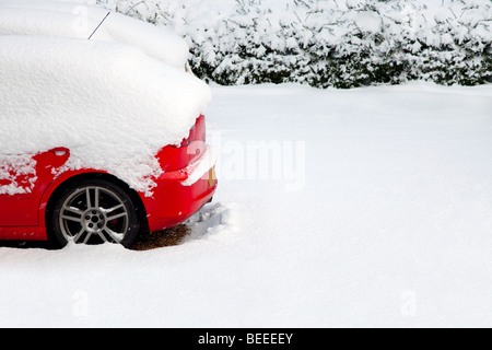 Arrière d'une voiture rouge couverts après une chute de neige récente Banque D'Images