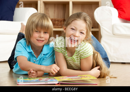 Deux jeunes enfants lecture livre à la maison Banque D'Images