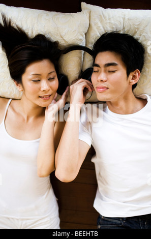 Asian young woman wearing headphones, les yeux fermés Banque D'Images