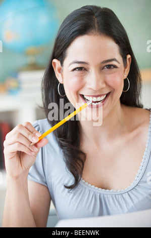 Smiling Hispanic woman biting gomme à crayon Banque D'Images