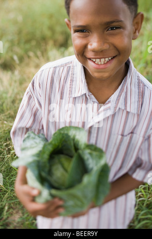 African boy holding cabbage in garden Banque D'Images