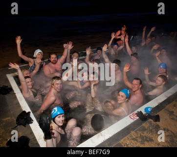 Groupe dans un bain à remous chauffé géothermie, soirée d'hiver, Reykjavik Islande Banque D'Images