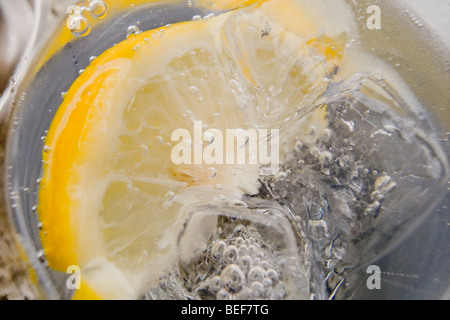 Un gros plan d'un verre de gin tonic, montrant des cubes de glace, des bulles et une tranche de citron Banque D'Images