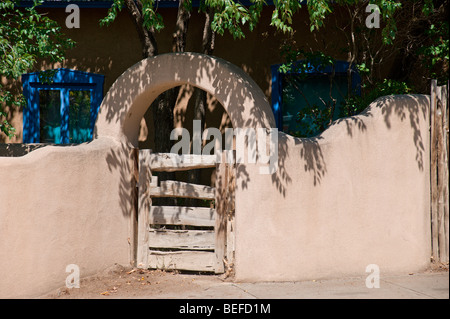 Un mur d'adobe avec un jardin secret gate trouvés à Taos, Nouveau Mexique. Banque D'Images