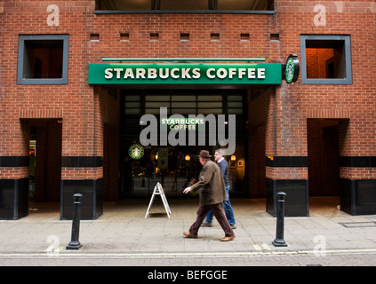 Deux mâles en passant devant un café Starbucks à Londres. Banque D'Images