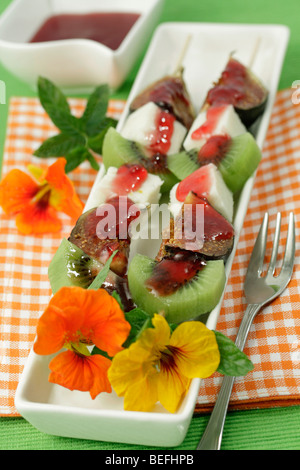 Brochettes avec des fruits et des fleurs. Recette disponible. Banque D'Images