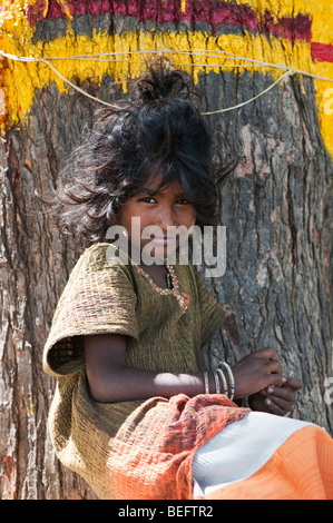 Jeune Indien street girl, assis en face d'un arbre, smiling Banque D'Images