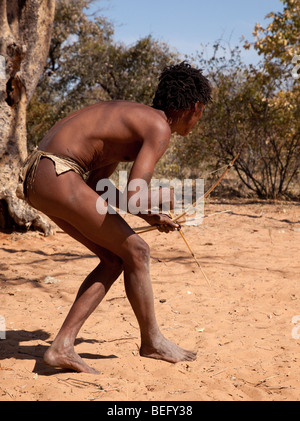 Village de San Namiba sur le bord du désert du Kalahari. Un chasseur San avec arc et flèche. Banque D'Images