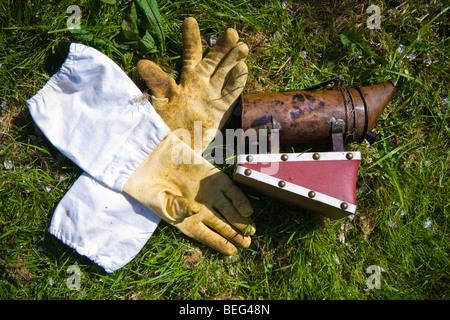 Apiculteur gants et fumeur, dans un verger, Sandford. North Somerset, Angleterre. Banque D'Images