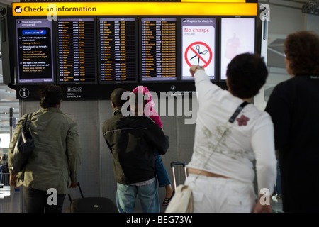 Lire l'information de départ des vols passagers dans le hall des départs du Terminal 5 à Heathrow. Banque D'Images