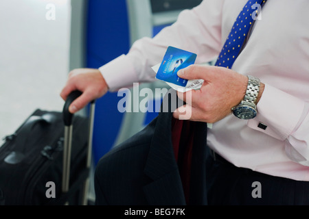 Un homme détient les documents de voyage qu'il vérifie à l'auto-British Airways à Heathrow borne de billetterie la borne 5 du Banque D'Images