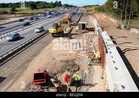 Projet d'élargissement de la route M25 avec débit en opération contre les hommes qui travaillent sur de nouveaux murs de retenue Banque D'Images