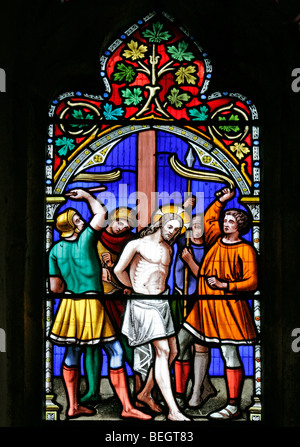 Une vitrail de William Warrington représentant Jésus-Christ en train d'être cloué sur le chemin de la crucifixion, St Mary la Vierge, Gunthorpe, Norfolk Banque D'Images