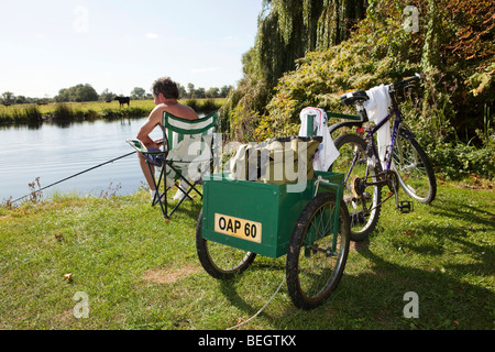 L'Angleterre, Cambridgeshire, Huntingdon, Hartford, pensionné avec remorque à vélo la pêche en rivière Great Ouse Banque D'Images