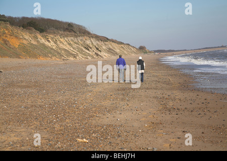 Deux personnes marchant sur la plage. Plage de Dunwich et falaises, côte de la mer du Nord, Suffolk, East Anglia, Angleterre Banque D'Images