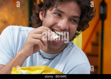 Close-up of a young man eating potato chips Banque D'Images