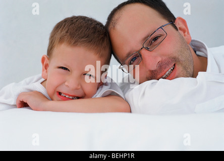 Portrait of a Mid adult man avec son fils couché sur le lit et souriant Banque D'Images