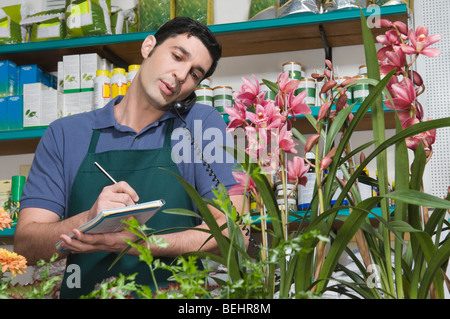 Homme, commis en prenant l'ordre dans un magasin de fleur Banque D'Images