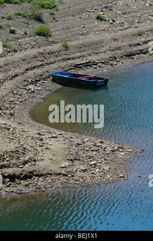 Bleu bateau sur un lac, le lac Lokvarsko, Gorski kotar, Croatie Banque D'Images