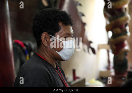 L'homme asiatique porte un masque chirurgical à l'intérieur d'un temple chinois à Bangkok. Banque D'Images