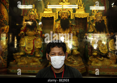 L'homme asiatique porte un masque chirurgical à l'intérieur d'un temple chinois à Bangkok. Banque D'Images