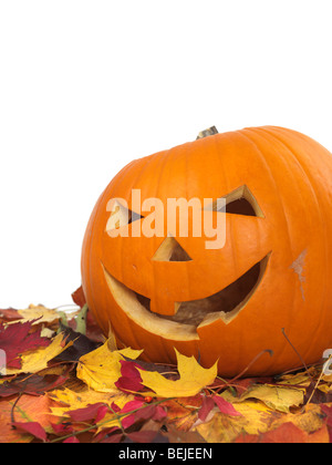Citrouille souriante sculptée sur les feuilles d'automne colorés Banque D'Images