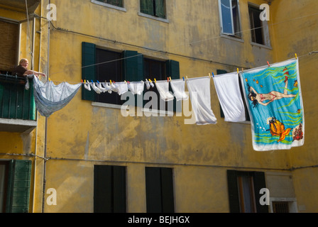 Femme de corde à linge traînant dehors le lavage humide de linge de famille pour sécher les cordes à linge publiques de l'autre côté de la rue. Logement public Arsenale, Venise Italie années 2000 Banque D'Images