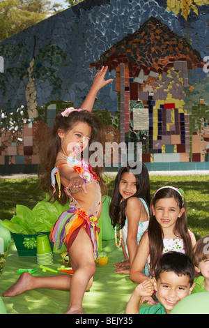 Fille dansant sur une table à la fête d'anniversaire avec ses quatre amis à côté d'elle Banque D'Images