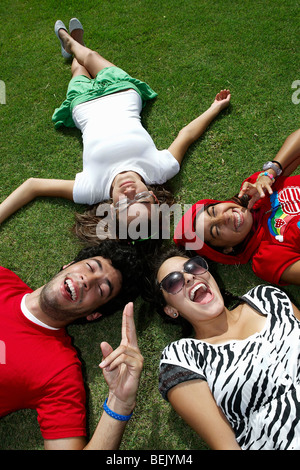 High angle view of a young man lying on grass avec trois jeunes femmes Banque D'Images