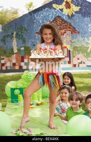 Girl holding birthday cake sur une table à un anniversaire avec ses quatre amis à côté d'elle Banque D'Images